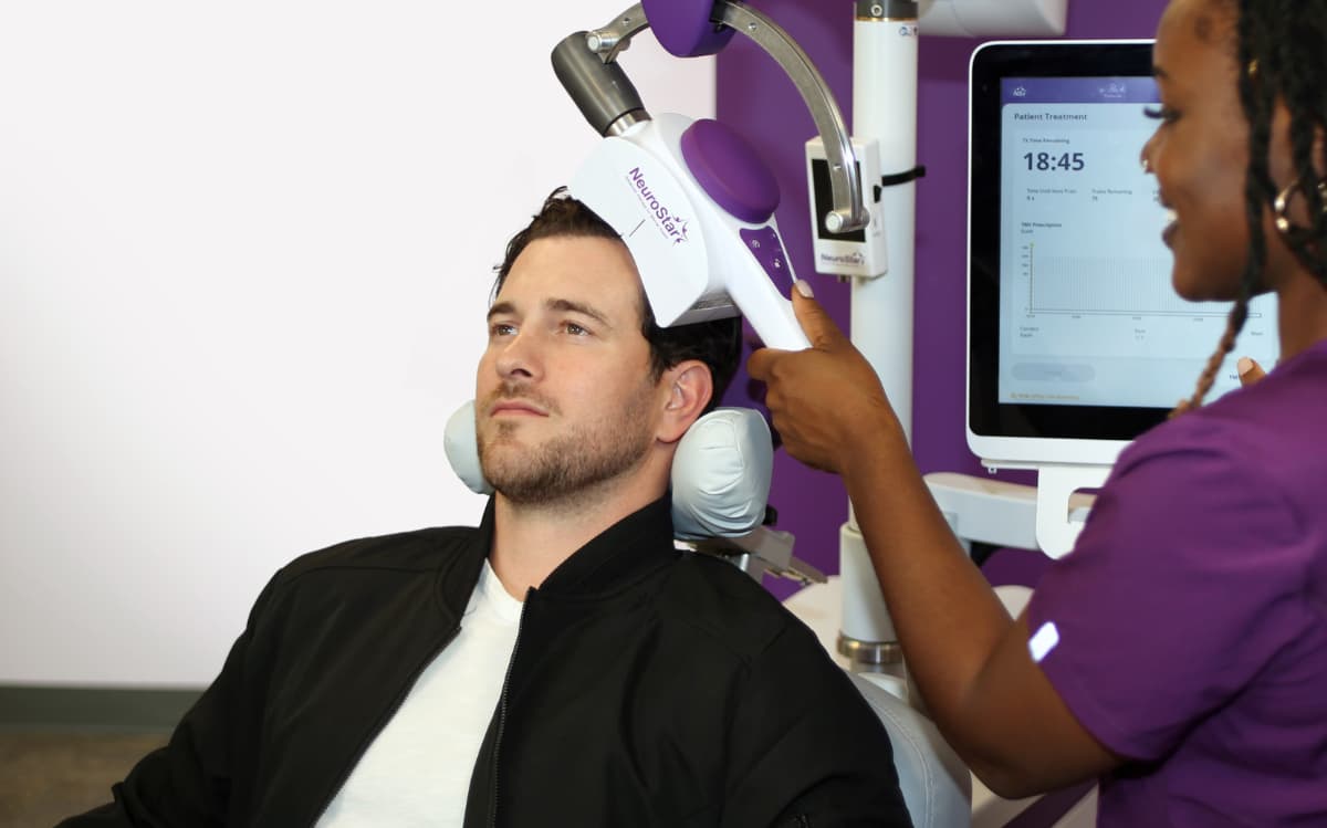 Patient receiving TMS treatment session, monitored by clinician for bipolar or mood disorder care.